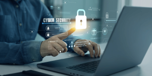 Business professional using a laptop interacting with a digital cybersecurity interface.